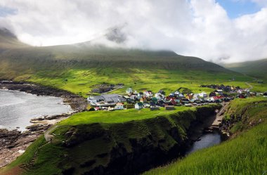 Faroe Adaları 'ndaki Gjogv köyünde renkli evler. Okyanus kıyılı dağ manzarası