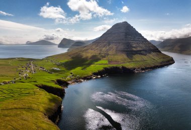 Hava manzarası fotoğrafçılığı. Vidareidi köyünün insansız hava aracından inanılmaz bir yaz manzarası. Güzel bir yaz manzarası. Faroe Adaları, Danimarka, Avrupa Vidoy Adası 'nın güneşli açık hava manzarası.