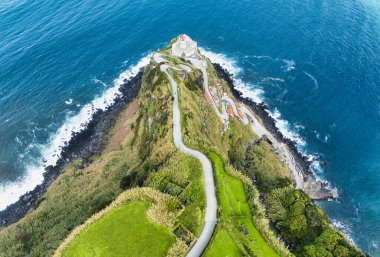 Aerial view of a curvy road leading to a lighthouse in the Azores Islands (Farol da Ponta do Arnel ) clipart