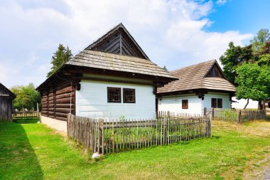 Arka planda halk evleri olan nadir ahşap çan kulesi. Bu korunmuş yapılar, Slovakya 'nın Liptov Köyü - Pribylina açık hava müzesinde bulunmaktadır.