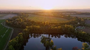 Slovakya 'nın gölü, tarlası, köyü ve ormanı üzerinde güzel bir günbatımı. Gün batımında hava manzarası. Yakut Sur
