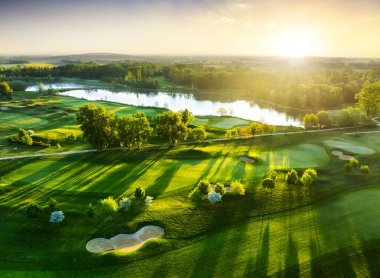 Bahar renkli ağaçlar ve göllerle golf sahasında gün batımının havadan görünüşü
