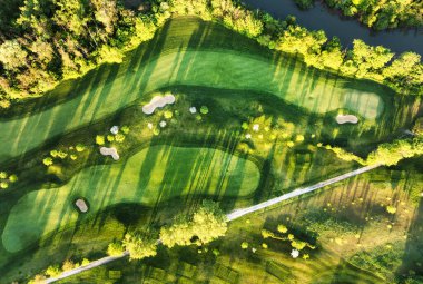 Golf sahasındaki yeşil çimlerin ve ağaçların havadan görünüşü