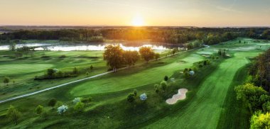 Gün batımında golf sahasında güzel bir gökyüzü ve kum tuzağı. İHA 'nın sığınağıyla golf sahasının manzaralı manzarası