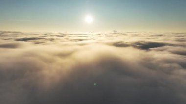 Gün batımında güneşle bulutların üzerinde uçuyor