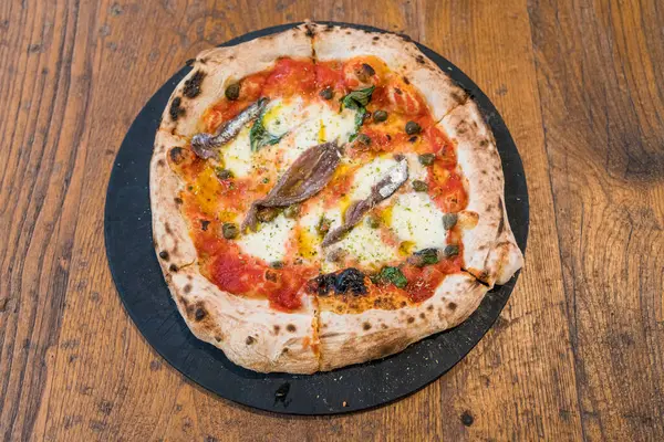 Ev yapımı Napoli usulü hamsi, zeytin ve mozzarella peynirli pizza..