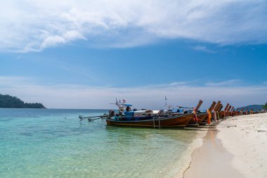 Traditional long tail boats in crystal clear water in Sai Khao Beach, Ra Wi Island, Southern of Thailand. clipart