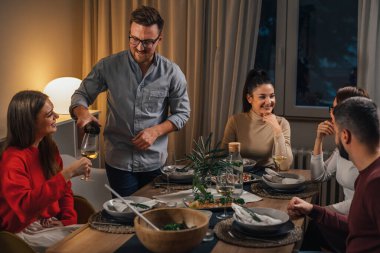 Adam ev yemeği partisinde şarap dolduruyor.