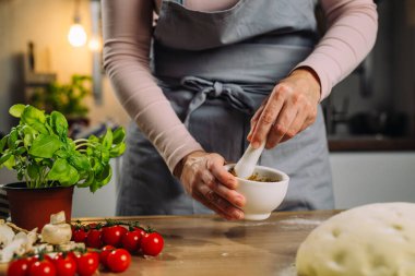 Kadının biri pizza için domates sosu hazırlıyor.