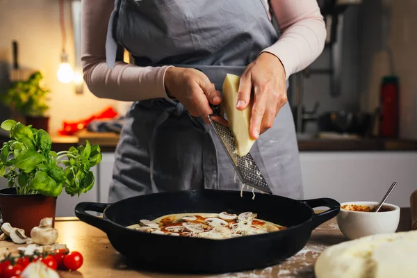 Pizzada peynir rendeleyen kadın