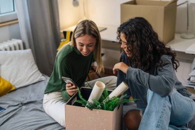 Genç kız öğrenciler odada cep telefonu kullanıyor.