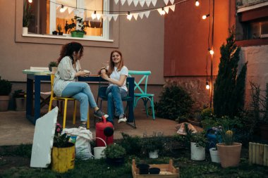 İki kız sandalyede oturuyor ve konuşuyor.