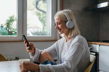 Genç kadın evde müzik dinliyor.