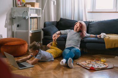 Anne ve oğlu yerde oturuyor.