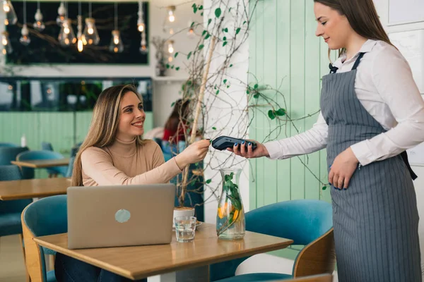 business woman pays the bill contactless