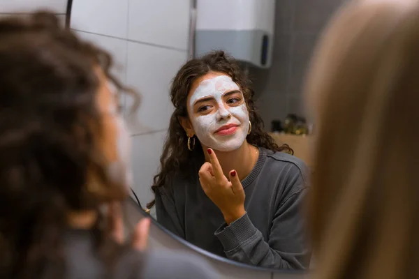 Jovem Mulher Coloca Máscara Facial Frente Espelho — Fotografia de Stock