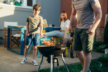 Baba ve oğul birlikte ızgara yapıyorlar.