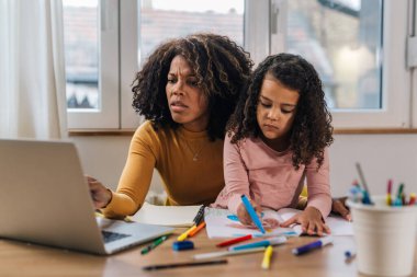 Karışık ırk anneleri evde finans işleriyle uğraşıyor ve kızı kucağında.