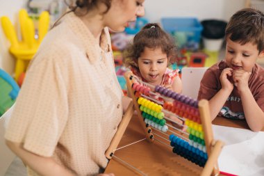 Çocuklar anaokulunda öğretmenlerinin yardımıyla saymayı öğreniyorlar.