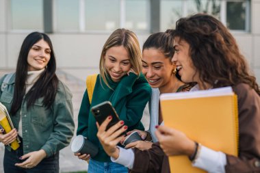 Arkadaşlar telefona bakarken gülerler.