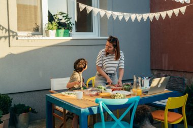 Sevgi dolu oğul annenin sebze kesmesine yardım eder.