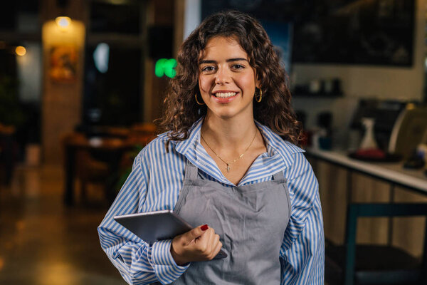 Waitress holds tablet and smiles to the camera