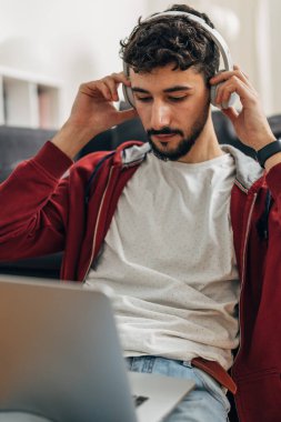 Genç adam kafasına kulaklık takıyor.