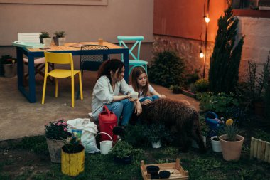 Anne ve kızı birlikte bahçeden çıktıktan sonra köpeklerine sarılıyorlar.