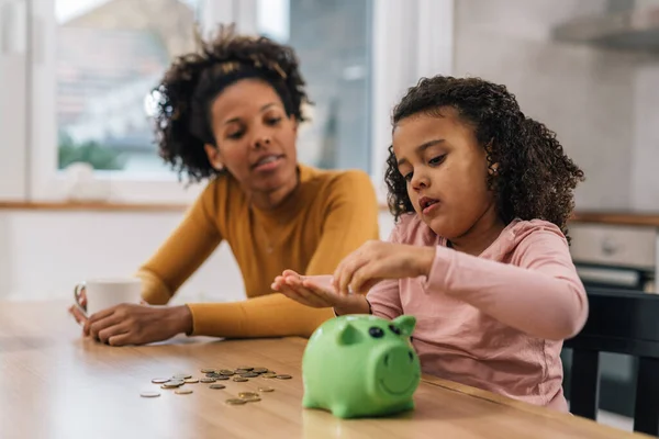 Daughter learns how to save money with a piggy bank