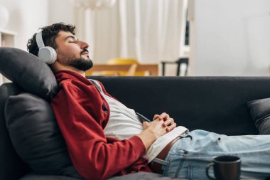 Adam evdeki kanepede, kulaklığı takmış dinleniyor.