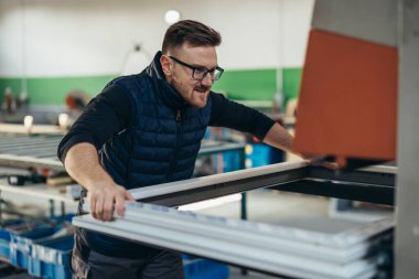 İşçi pencere çerçevesini bir makineye yerleştirir