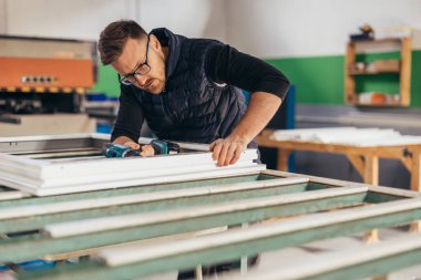 Adam pencere çerçevesinde tornavida kullanıyor. PVC pencere çerçevelerinin üretimi