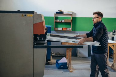 İşçi bir pencere çerçevesini makineye yerleştirir