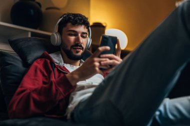 Adam evde tek başına oturuyor ve kanepede dinleniyor.