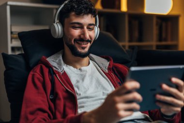 Genç adam tablette video oyunu oynuyor.