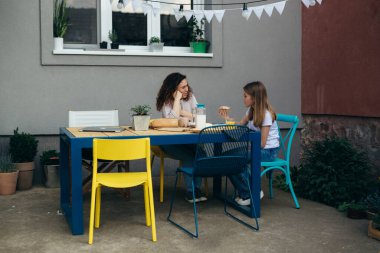 Anne ve kızı arka bahçede sohbet ediyorlar.