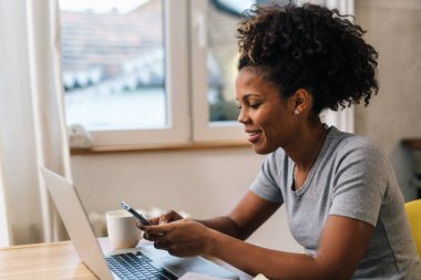 Businesswoman sits at home and uses mobile phone and laptop