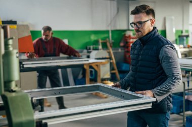Worker is operating a machine for making PVC window frames