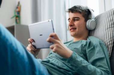 Teenage boy uses a tablet in his room