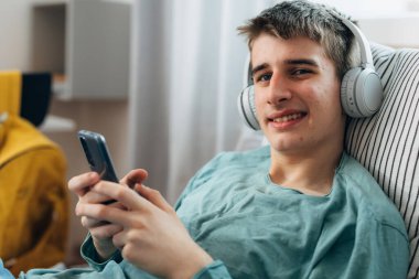 Adolescent boy with headphones looks at the camera