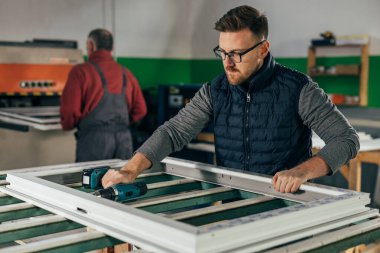 Middle aged worker is screwing the window frame