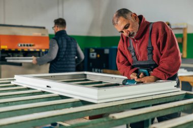 Handyman is screwing the window frame
