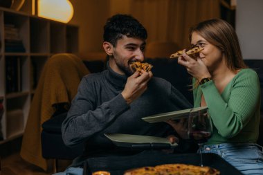 Genç çift akşam yemeğinde pizza yiyor.