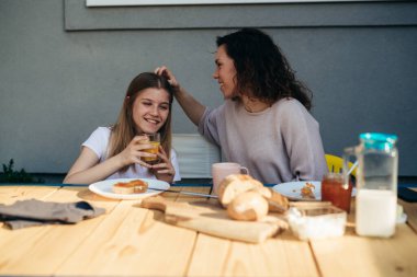 Mother and daughter are having enjoyable breakfast in the backyard