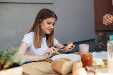 Teenage girl is spreading butter on bread