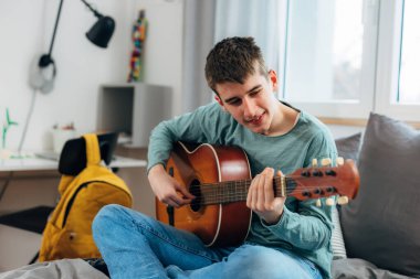 Teenage boy enjoys playing the guitar
