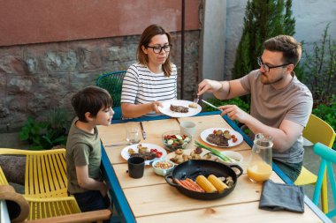 Family eats barbeque for lunch in the backyard