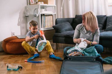 Mother is packing a suitcase for a trip with her son