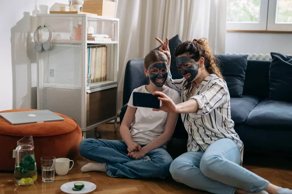 Mother and daughter take pictures of themselves with face masks on