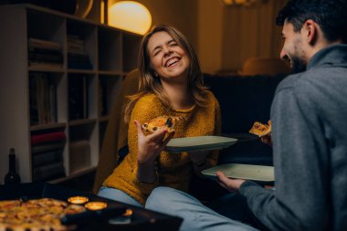 Genç çift akşam yemeği için birlikte pizza yiyorlar.